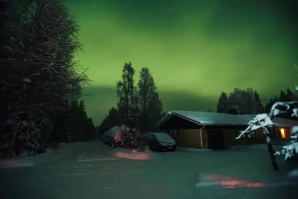 Yeşil aurora gece gökyüzü evin üstünde, ormandaki kar içinde Rovaniemi, Laponya 'da