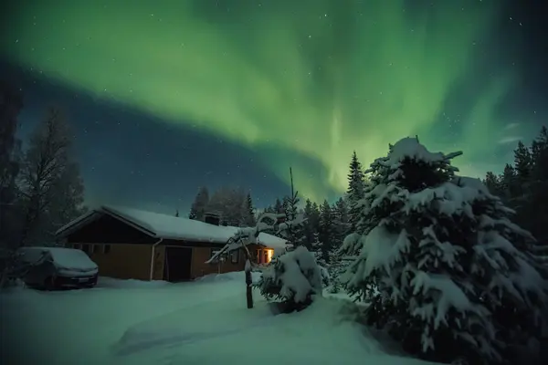 Kuzey ışıkları Rovaniemi 'de ormandaki karlı evin üzerinde, kışın Laponya' da