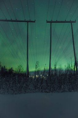 Gökyüzünde Aurora borealis Rovaniemi, Laponya 'da elektrik hatlarının arkasında