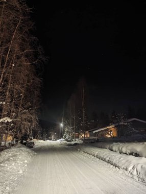 Karlı Rovaniemi sokağı gece, Laponya 'da sönük bir aurora ile