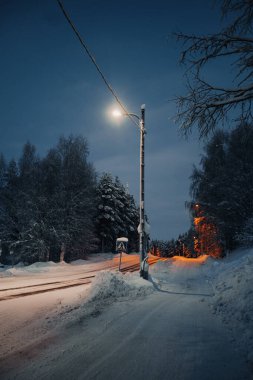 Rovaniemi, Laponya 'da kışın alacakaranlıkta karlı yolun üzerindeki sokak lambası.