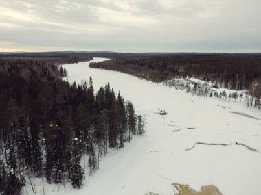 Rovaniemi yakınlarındaki Laponya ormanından geçen donmuş nehrin havadan görüntüsü.