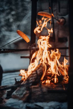 Kışın Korouoma Kanyon Laponya 'sında bir yangında sosis pişirmek.