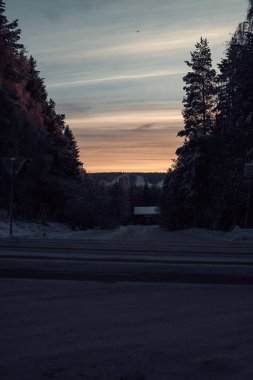 Kışın Laponya, Rovaniemi 'de karlı caddenin üzerinde güneş batıyor.