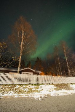 Rovaniemi, Laponya 'da Aurora Borealis' in altındaki kırmızı ahşap ev.