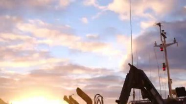 Norveç 'te Tromso limanındaki balıkçı teknelerinin arkasında güneş batıyor.