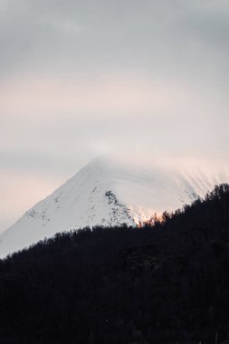 Sonbaharda Norveç 'in Tromso kentinin dışındaki kutuplarda gün batımında karlı dağ