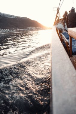 Tromso, Norveç 'teki balıkçı teknesinin altında fiyort sularının üzerine güneş batıyor.