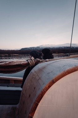 İnsanlar gün batımında Norveç, Tromso 'daki ahşap tekneden Kuzey Kutbu fiyortlarına bakıyor.