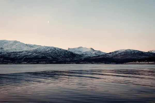 Norveç, Tromso 'da gün batımında fiyordun yanındaki Kuzey Kutbu dağlarının manzara görüntüsü