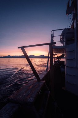 Sonbaharda Norveç 'in Tromso kentinin dışındaki Kuzey Kutbu fiyordunun üzerinde pembe gün batımı gökyüzü