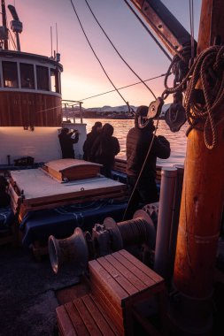 Tromso, Norveç 'teki fiyortta geleneksel ahşap balıkçı teknesinin güvertesindeki insanlar.