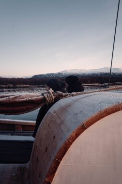 İnsanlar gün batımında Norveç, Tromso 'daki ahşap tekneden Kuzey Kutbu fiyortlarına bakıyor.