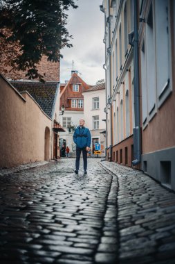 Tallinn, Estonya 'da mavi paltolu bir adam eski kasaba caddesinde yürüyor.