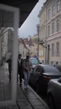 Eski kasaba Tallinn, Estonya 'da insanlar arabaların önünden yürüyorlar, dikey