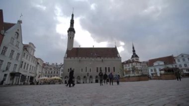 Tallinn Estonya belediye binasının dışındaki eski kasaba meydanında yürüyen insanlar