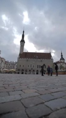 Tallinn Estonya belediye binasının dışındaki eski kasaba meydanında yürüyen insanlar, dikey
