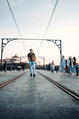 Man walking between tram lines on top of Ponte Dom Luis I in Porto, Portugal clipart