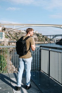Portekiz, Porto 'da Douro Nehri' nin yanında sırt çantası taşıyan bir adam duruyordu.