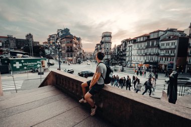 Man sat on wall at sunset outside Sao Bento station in Porto, Portugal clipart