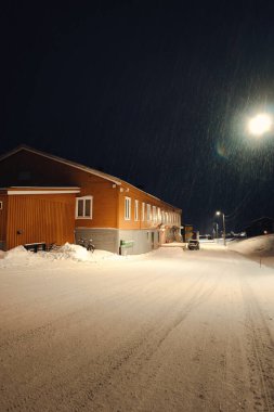 Kışın Nybyen 'de karlı yolun yanındaki kahverengi ahşap bina, Longyear byen.
