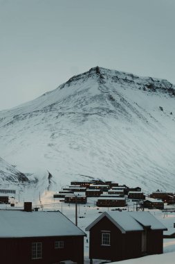 Snowy apartment buildings under mountain in Longyearbyen, Svalbard clipart