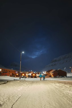 Longyearbyen 'deki evler arasında yürüyen insanlar, kutup gecelerinde Svalbard