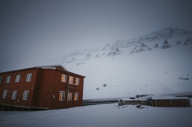 Longyear 'daki Gjestehuset pansiyonunun arkasındaki karlı dağlar, Svalbard siste.
