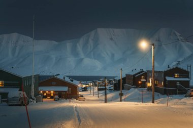 Longyearbyen kasabası, Svalbard kutup gecesinde karlı Kuzey Kutbu fiyortlarının önünde