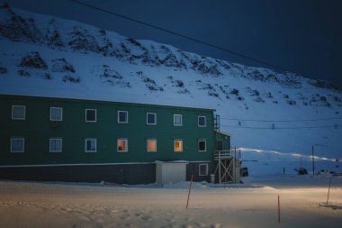 Longyear, Svalbard 'daki karlı kutup dağlarının önündeki yeşil bina