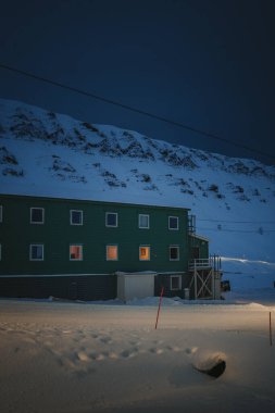 Longyear, Svalbard 'daki karlı dağların önündeki yeşil bina