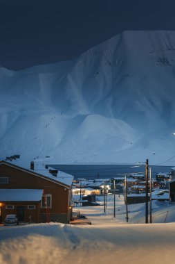 Longyear, Svalbard 'ın kutup gecesi manzarası karlı Arktik fiyordun önünde.