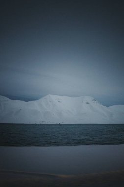 Snowy arctic mountains by fjord in the polar night in Longyearbyen, Svalbard clipart