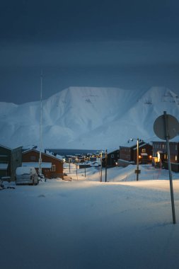 Kutup gecesinde Longyear, Svalbard 'daki karlı fiyorda giden yola bak.