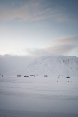 Longyear, Svalbard 'ın dışında, gün batımında karlı kutuplarda kulübeler.