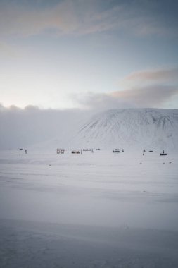 Kuzey Kutbu 'nda, Longyearbyen' de, Svalbard 'da kar altında kulübelerin üzerinde hava kararacak.