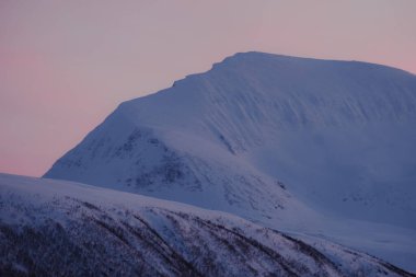 Tromsdalstinden Dağı 'nın zirvesi Tromso, Norveç' te pembe günbatımı gökyüzüne karşı