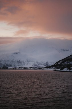 Kuzey Norveç 'te bulutların altındaki karlı dağlar altın saat.