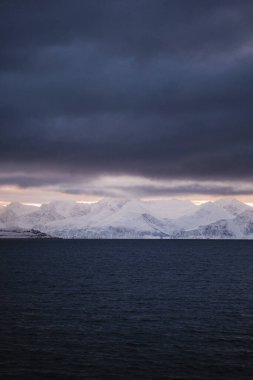 Gün batımında gri bulutların altındaki karlı dağlar, Kuzey Norveç 'teki Lyngen Alpleri