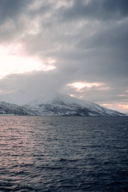 Kuzey Norveç 'in kutup kışında, Lyngen Alpleri' nin üzerindeki bulutlar gün batımında gökyüzüne yükselir.