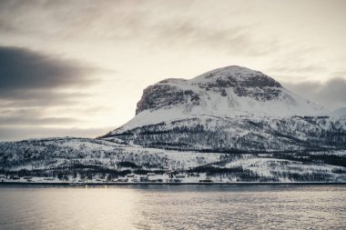 Kuzey Arktik Norveç 'teki Lyngen Alplerinde gün batımında karlı kayalık dağ zirvesi