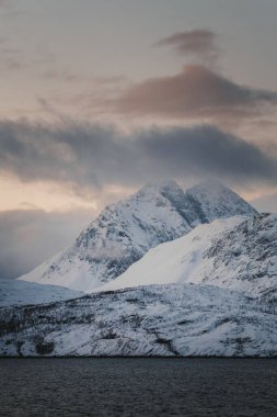 Karlı Lyngen Alp Dağları Kuzey Norveç 'te gün batımında bulutların altında