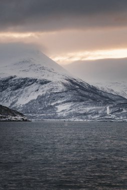 Kuzey Norveç 'te gün batımında karlı Lyngen Alplerinin yanındaki fiyort