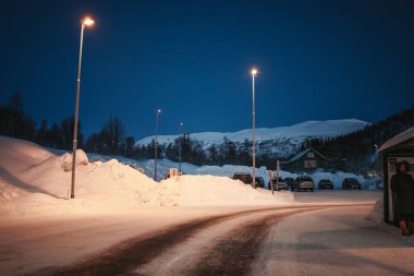 Norveç, Tromso yakınlarındaki Eidkjosen otobüs durağından alacakaranlıkta karlı dağlar görünüyor..