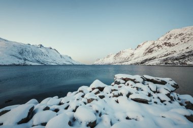 Norveç, Tromso yakınlarında güneşli bir kış gününde karlı Ersfjord 'un manzara görüntüsü.