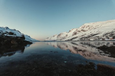 Norveç, Tromso yakınlarındaki Ersfjord 'da dağların yansımasıyla karlı arktik okyanus.