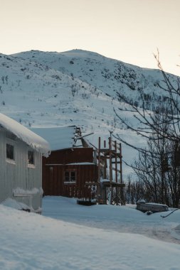Ersfjordbotn, Tromso, Norveç 'teki karlı tepenin önünde çürüyen ahşap kulübe.