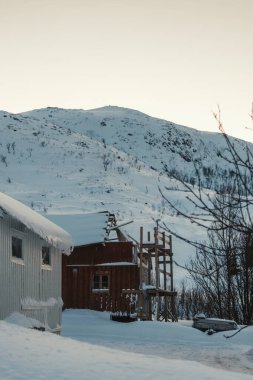 Ersfjordbotn, Tromso Norveç 'teki karlı tepenin önündeki ahşap kulübeyi dağıtıyor..