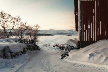 Kışın Finlandiya 'da donmuş Kilpisjarvi Gölü kıyısındaki karlı tepelerde gün doğumu.
