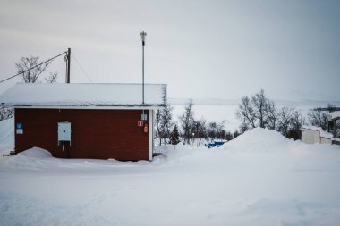 Finlandiya 'daki donmuş Kilpisjarvi Gölü' nün kenarındaki karda kırmızı ahşap kulübe..
